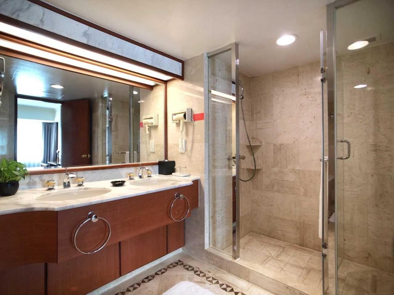 Evergreen Laurel Hotel - Taichung Exteriör bild The photo depicts a modern bathroom featuring a double vanity sink with a marble countertop and wooden cabinetry. Above the sinks, there is a large mirror with integrated lighting. To one side, there is a shower enclosed in glass, showcasing a sleek 
